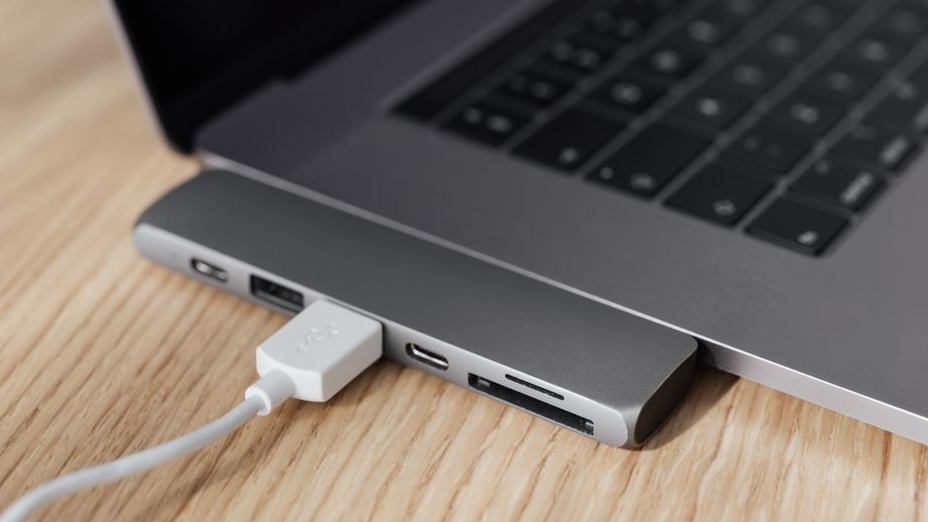 나무 책상 위 노트북에 연결된 USB-C 허브와 케이블